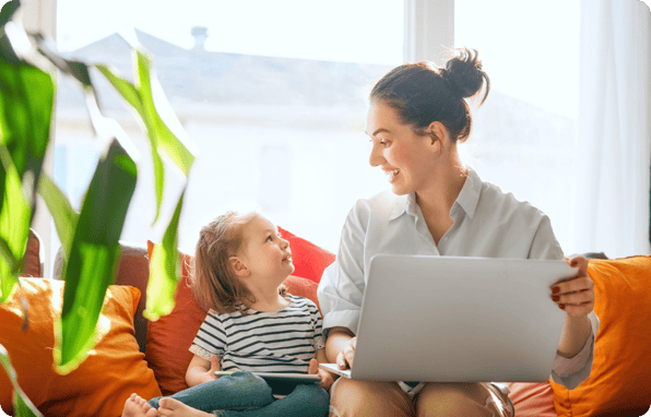 Parent filling out a childcare enrollment form on a laptop while sitting with their child at home.